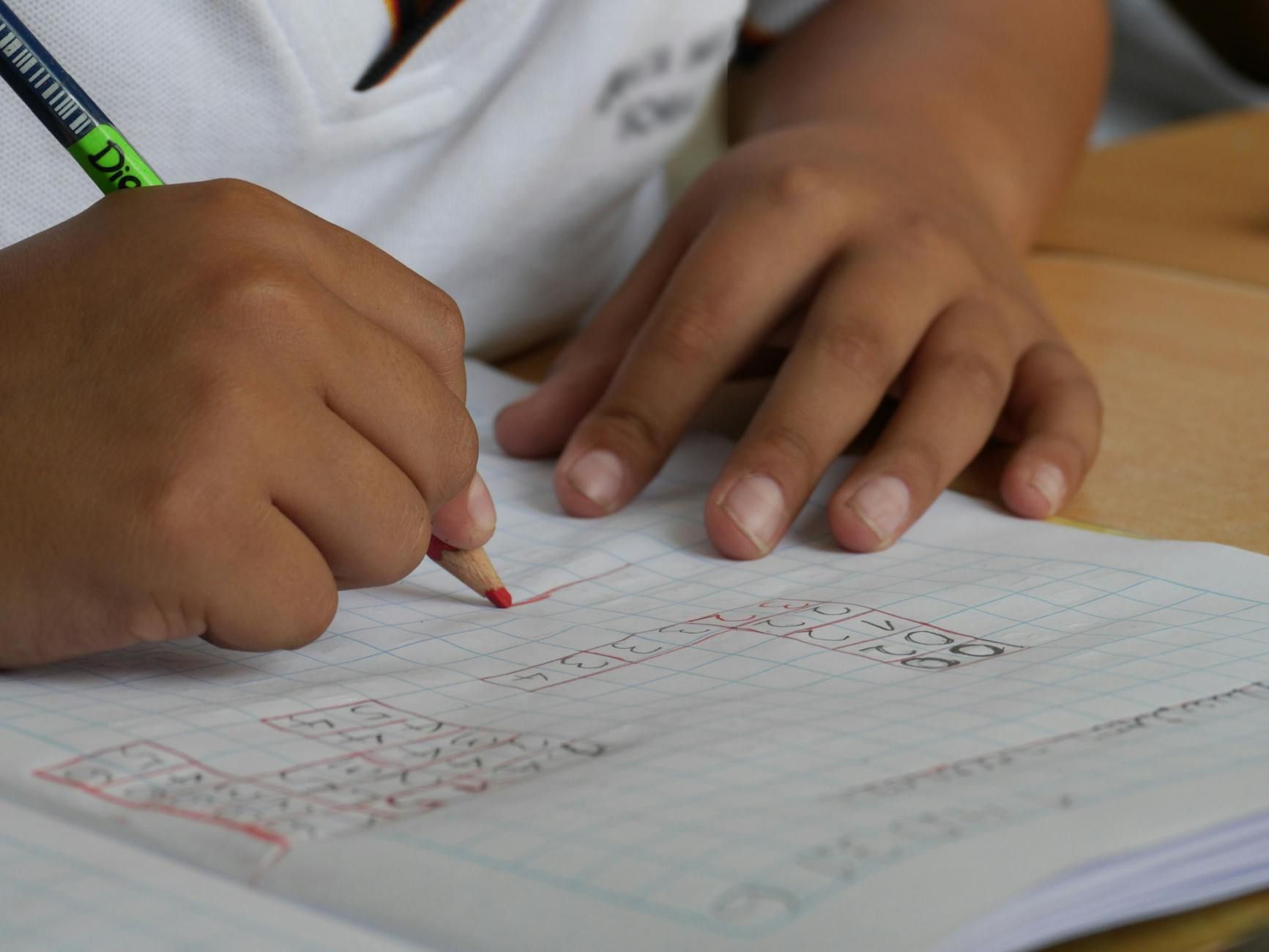 Close up of a students pencil marking up graph paper in a classroom.
